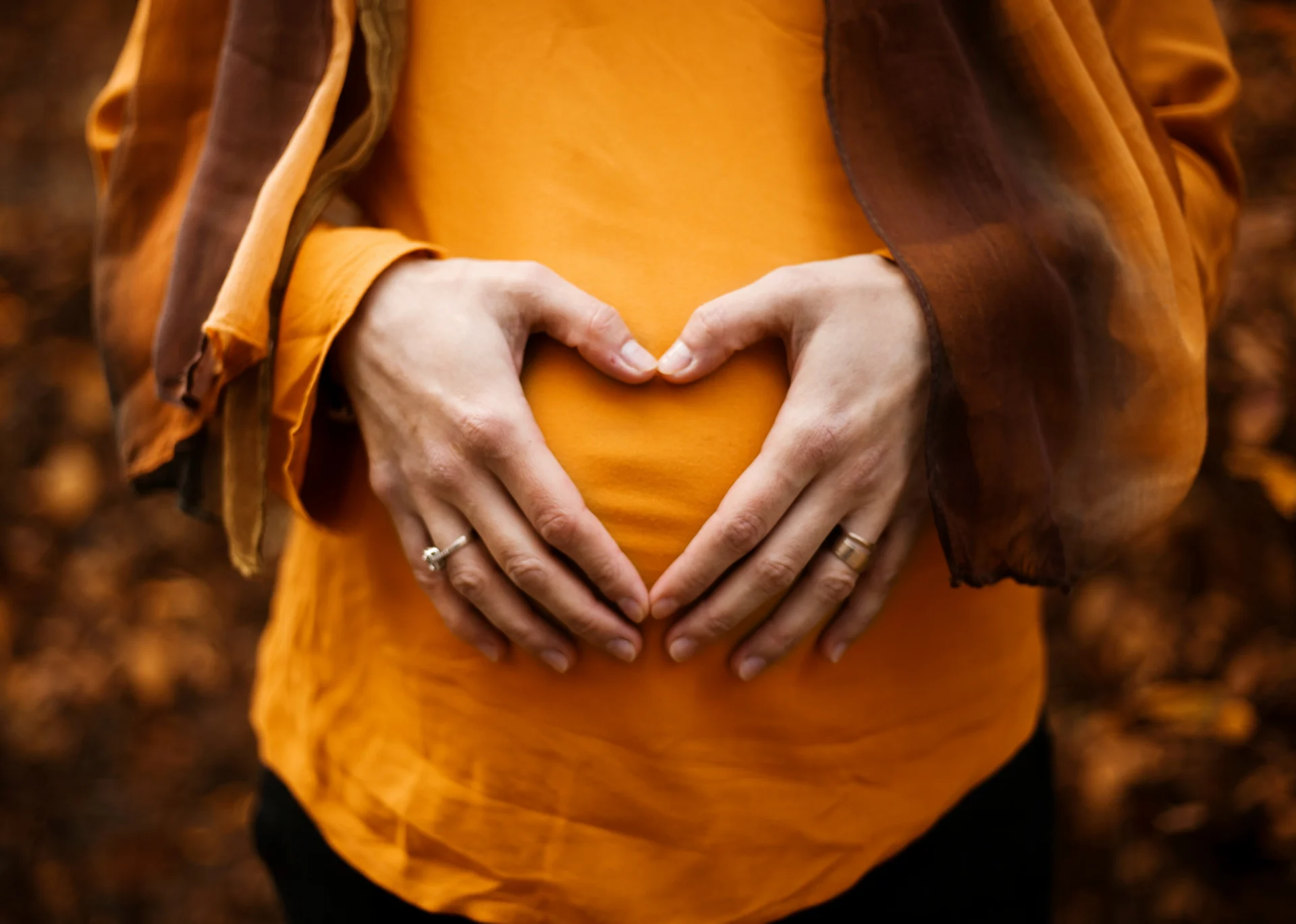 A pregnant lady with a heart shape from her hands held over her belly. She's put her will in place already to protect her new baby.