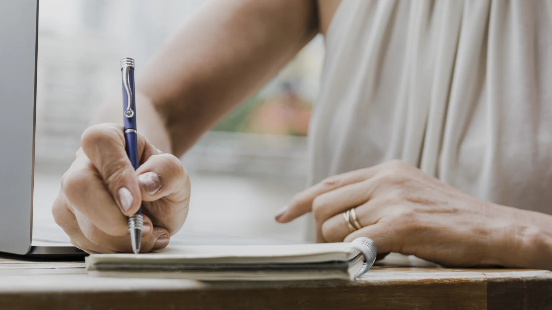 A person writing in a notebook with the pen resting above. They are making notes before booking in to write their will professionally.