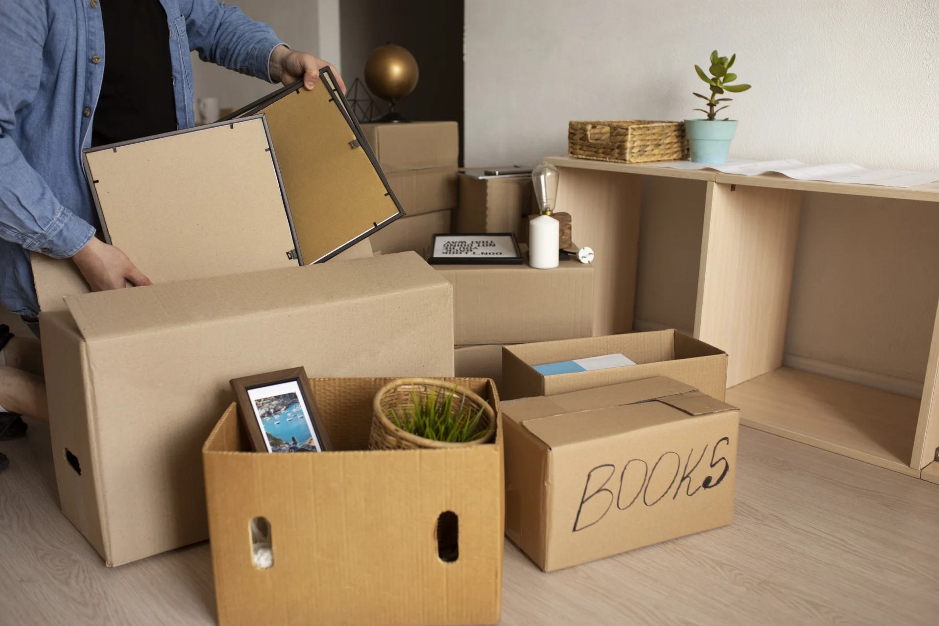 A lounge full of packing boxes and empty shelves. Representing someone buying their first home and knowing they need to get a will in place.